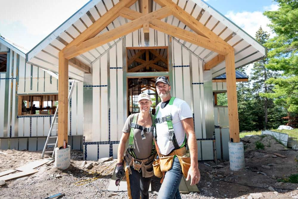 Happy homeowners posing in front of their cabin ©robert lowdon
