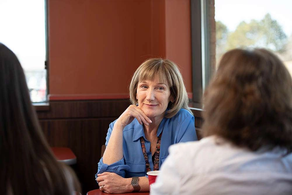 Three people share a conversation of coffee. © robert lowdon