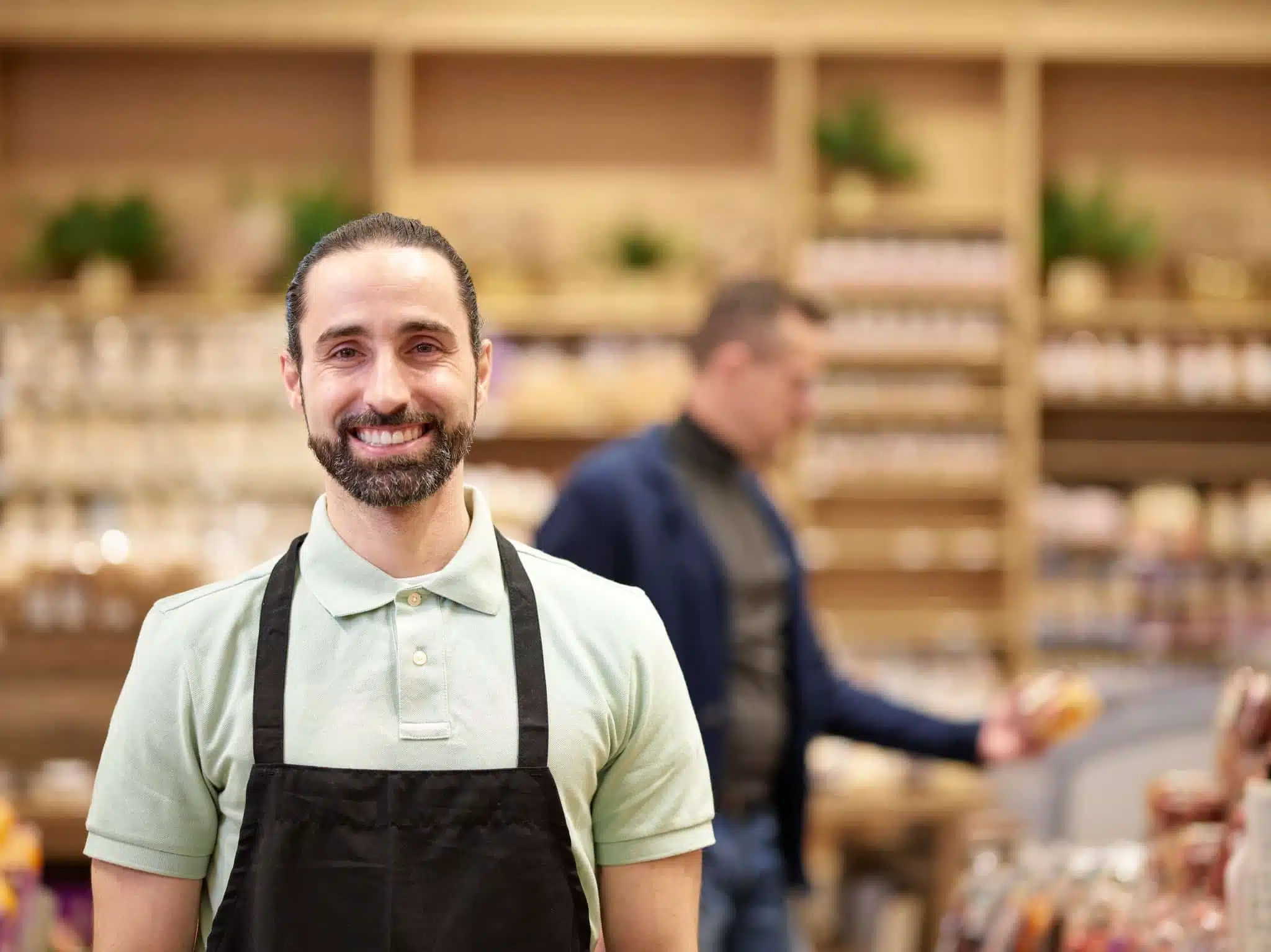 Grocery store aisle stocker with customer shopping in background.