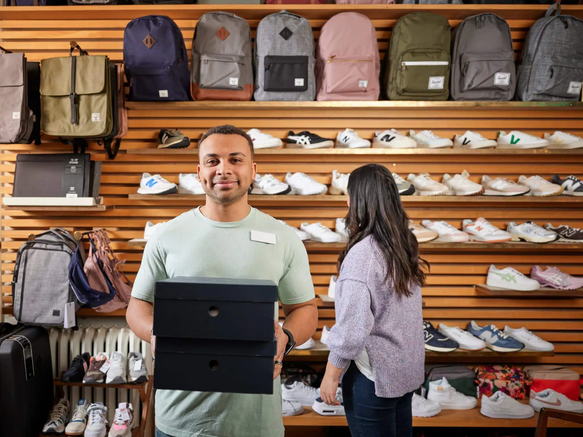 Retail store employee with shoe boxes for customer to try on