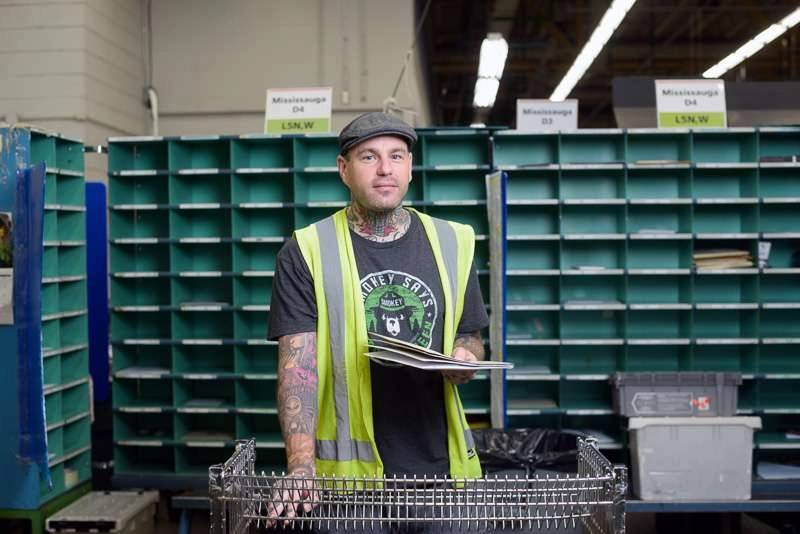 Worker with tattoos sorts mail at work