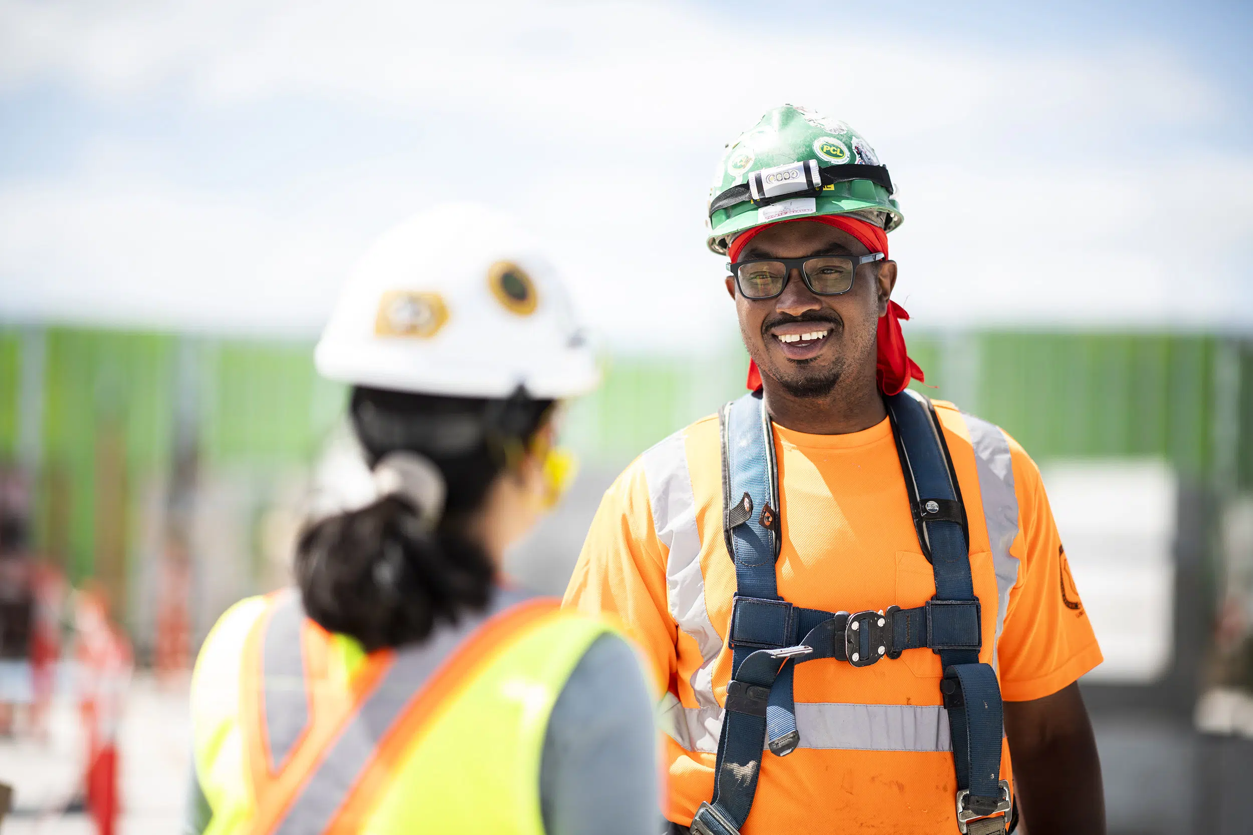 A male worker talks to a female worker on a construction site.