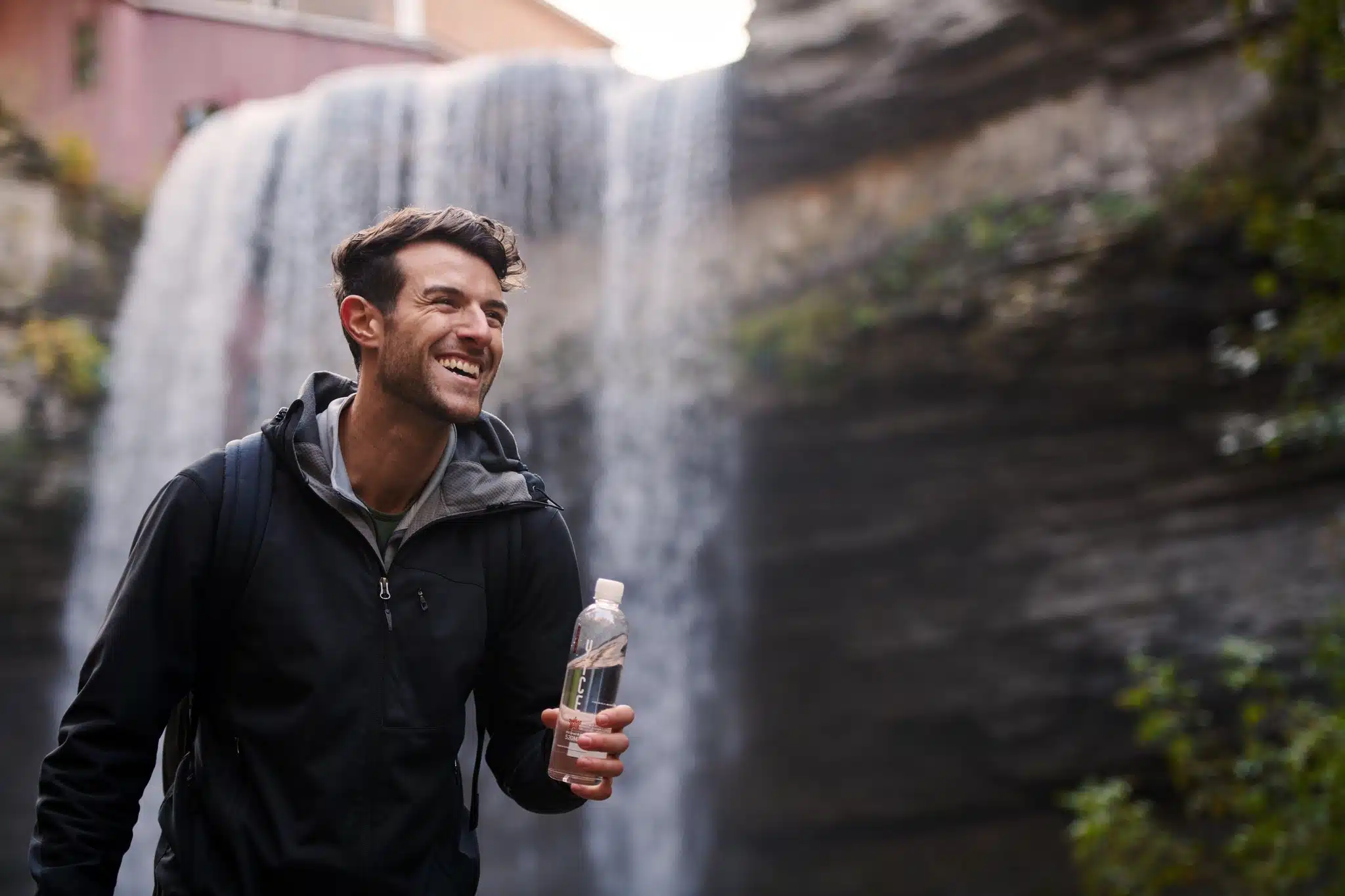Hiker at waterfall with newly branded water bottle.