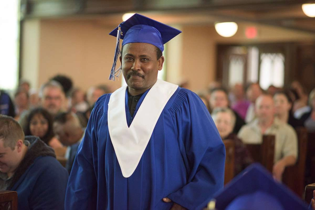 Editorial Photography For Cdi College - Editorial Photgrapher Robert Lowdon Cdi 14 A student stands, preparing to approach the stage. The warm smile on the graduand’s face evokes a sense of pride and anticipationt. A shallow depth of field is used to bring the student into focus and softly blur the seated guests in the background.
