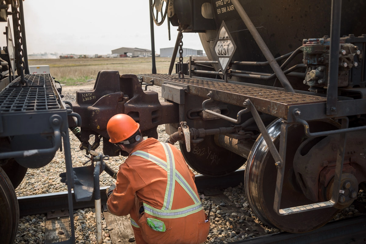 Worker attaches air brake line on rail cars