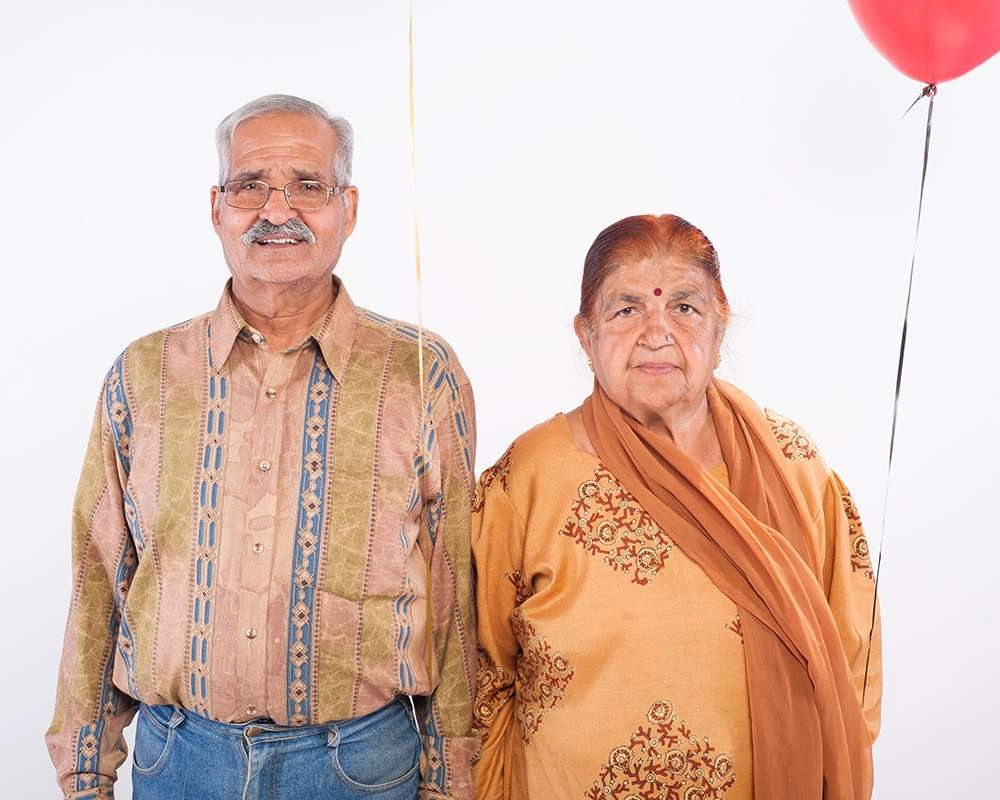 Couple poses in front of white background with balloon