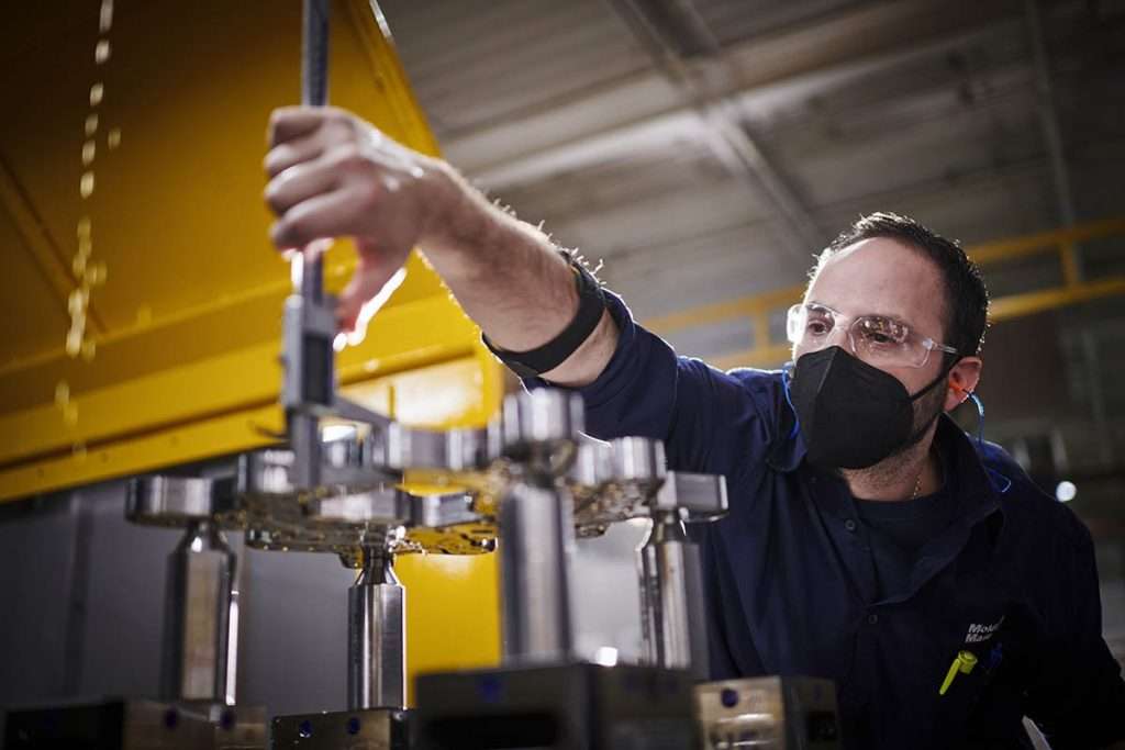 worker tightens bolt on machine