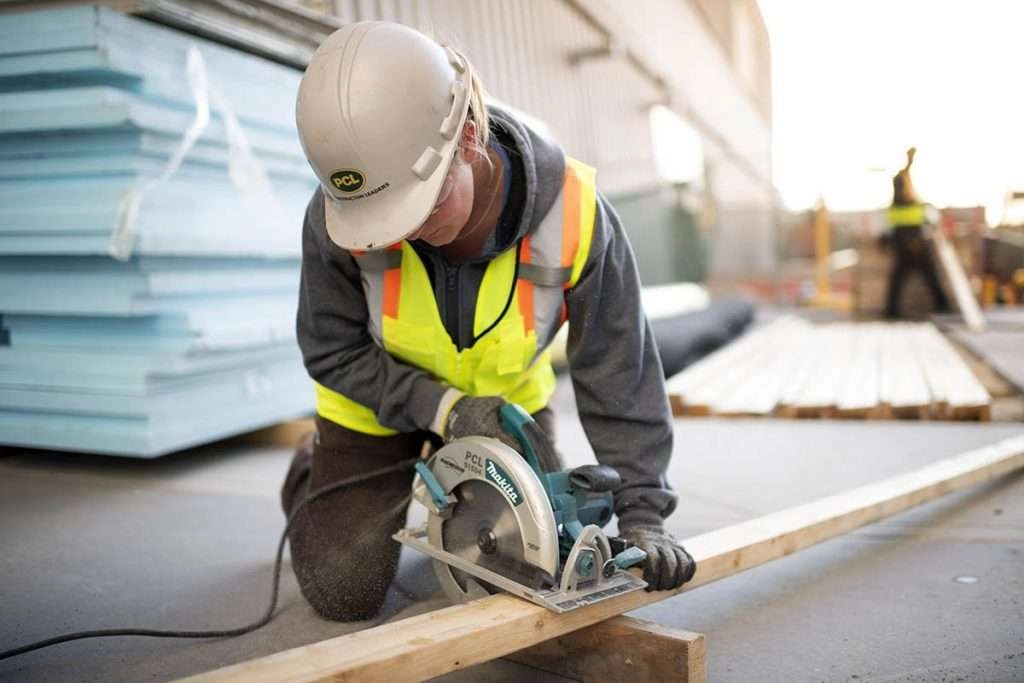 Female construction worker using saw